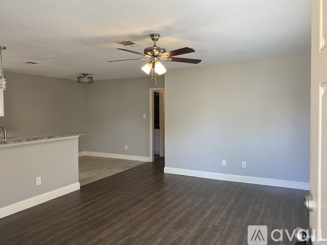 A room with a ceiling fan and a door at the end.
