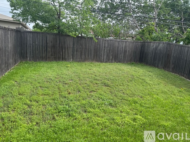 A backyard with a wooden fence and green grass.
