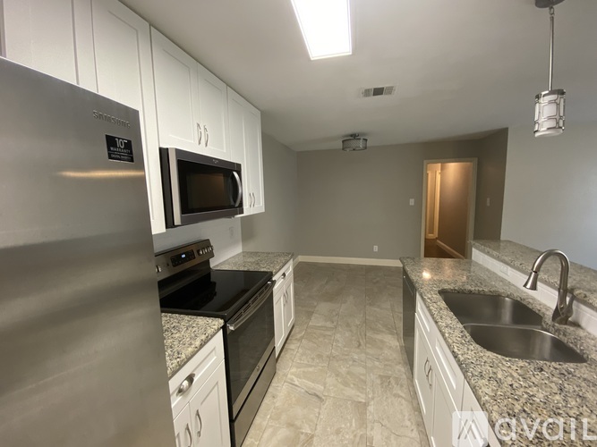 A kitchen with a stainless steel refrigerator and a granite countertop.