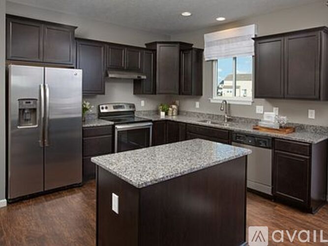 A kitchen with dark brown cabinets and a granite countertop.