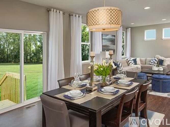 A dining room with a table set for two and a view of a backyard.