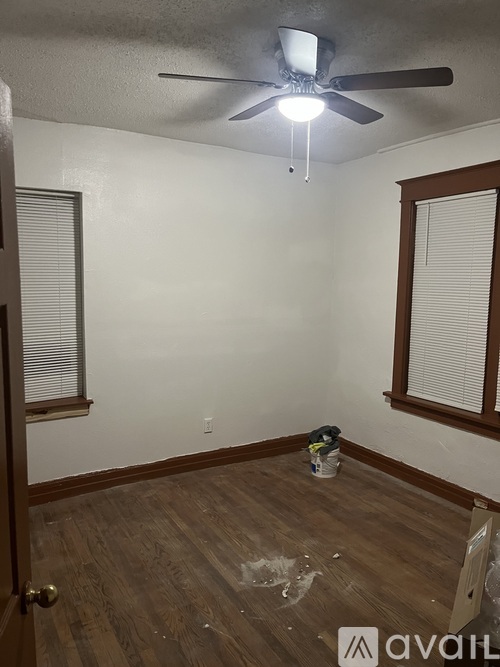 A room with a ceiling fan and a bucket on the floor.