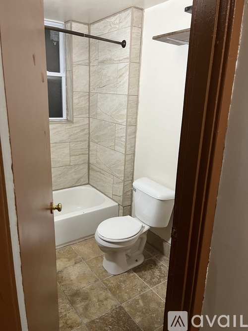 A bathroom with a toilet, tub, and tiled walls.