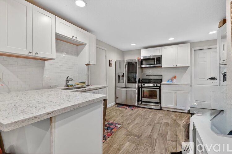 A kitchen with white cabinets and a marble countertop.