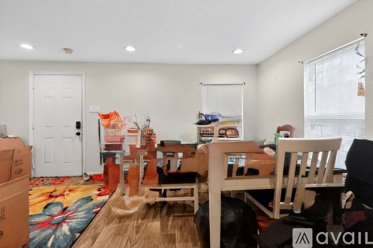 A room with a dining table and chairs is shown with boxes on the floor.