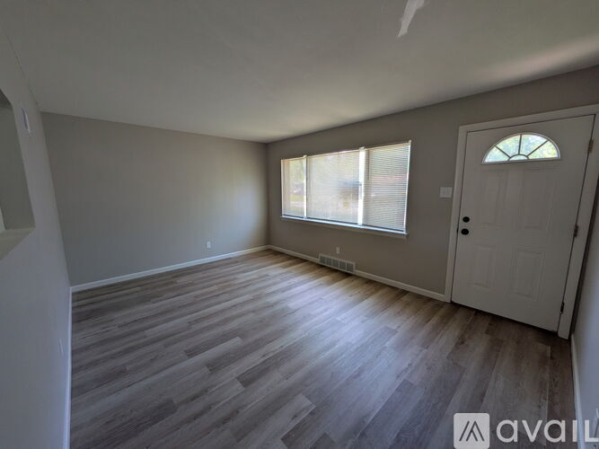 A room with wooden flooring and a window with blinds.