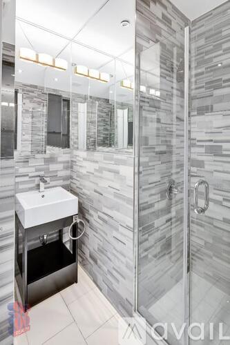 A bathroom with a walk-in shower and a white sink.