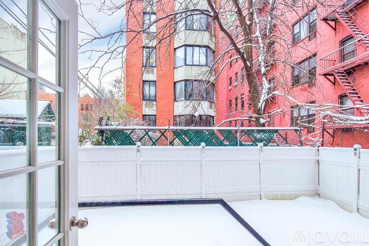 A red building with a white fence and a tree in front of it.