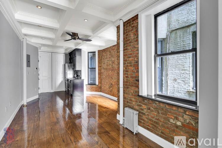 A spacious room with a brick wall and wooden floors.