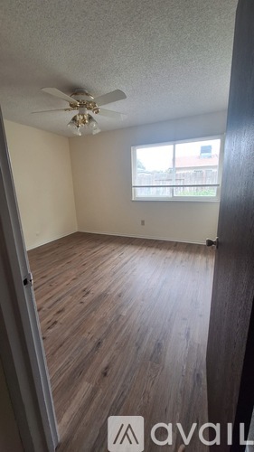 A room with a ceiling fan and wooden flooring.