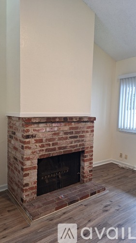 A brick fireplace in a room with wooden floors.