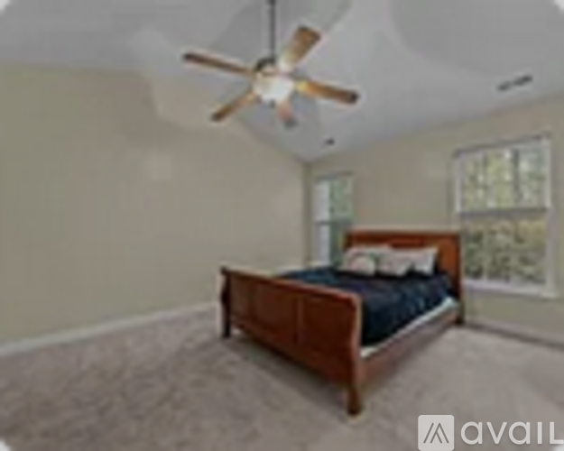A bedroom with a bed, a ceiling fan, and a window.