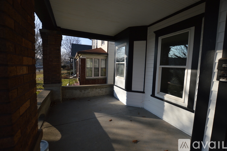A porch with a brick column and a white wall.