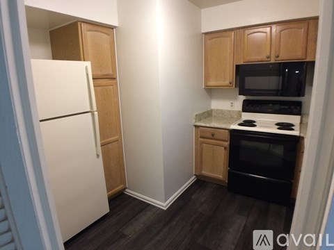A kitchen with a white refrigerator, wooden cabinets, and a black stove top oven.