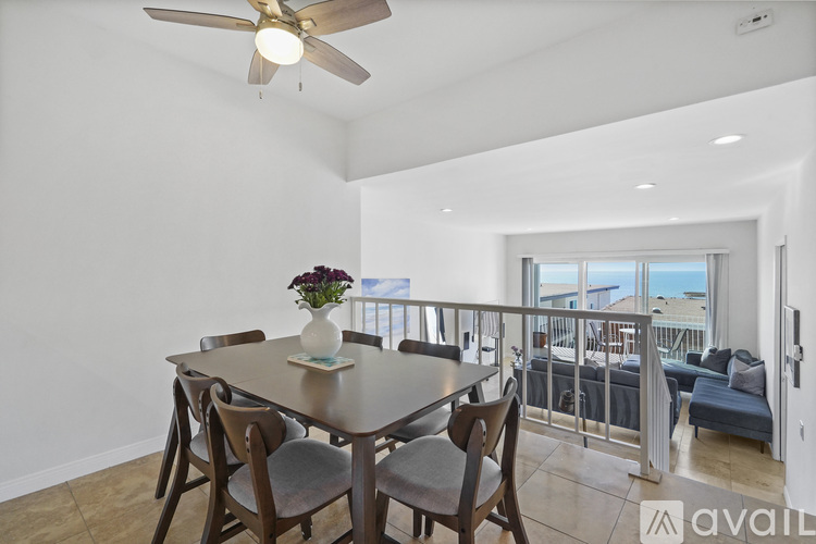 A dining room with a table set for four and a balcony with a view of the ocean.