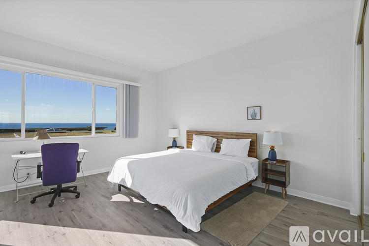 A bedroom with a large bed and a chair by the window.