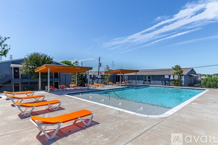 A pool with orange sun loungers and a blue sky.