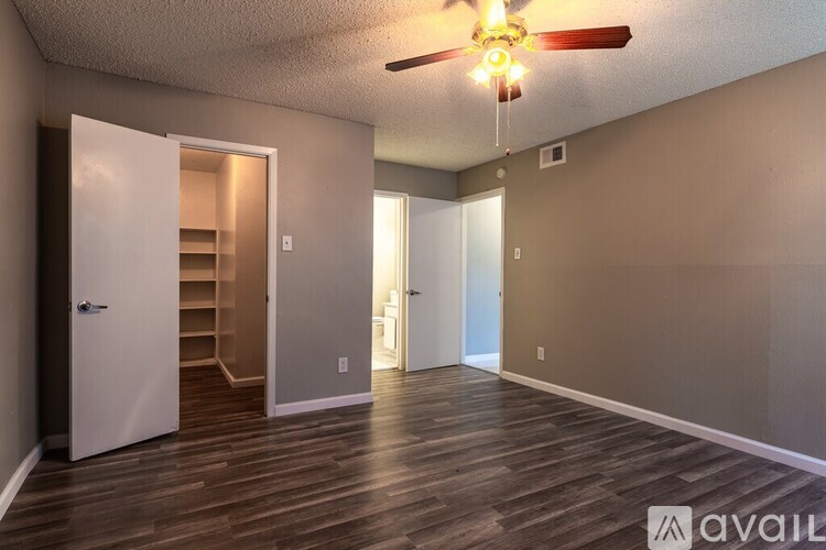 A room with a ceiling fan and wooden flooring.