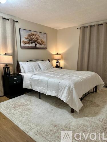 A bedroom with a large bed and two lamps.