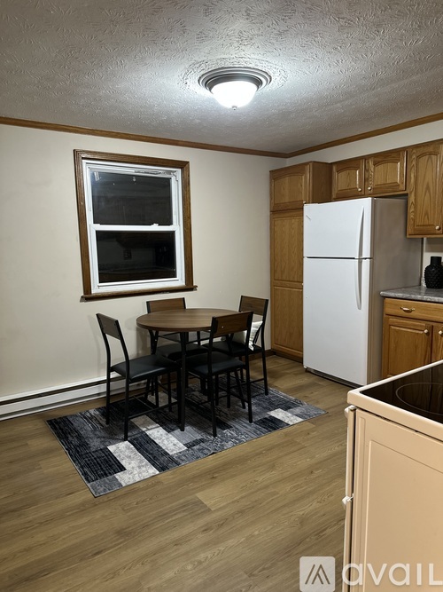 A kitchen with a table and chairs and a refrigerator.