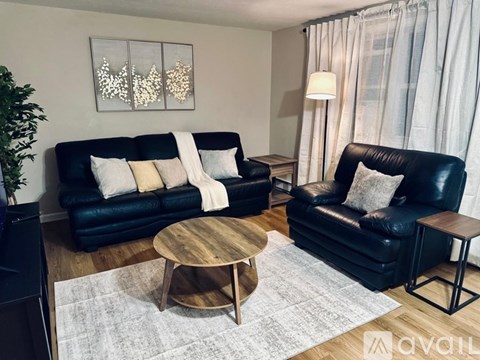 A living room with two black leather couches and a wooden coffee table.