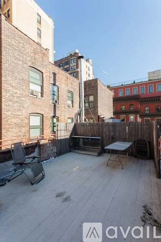 A wooden deck with a table and chairs overlooks a city street.