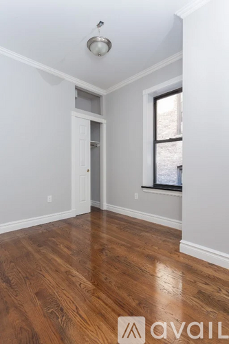 A room with wooden floors and a window with a view of a snowy landscape.