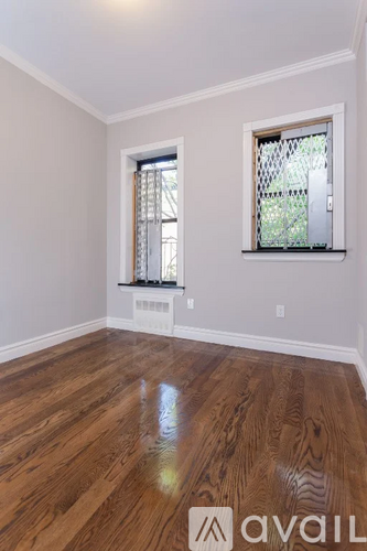 A room with wooden floors and two windows.