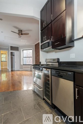 A modern kitchen with dark wood cabinets and stainless steel appliances.