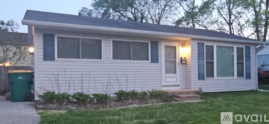 A house with a front yard and a trash can.