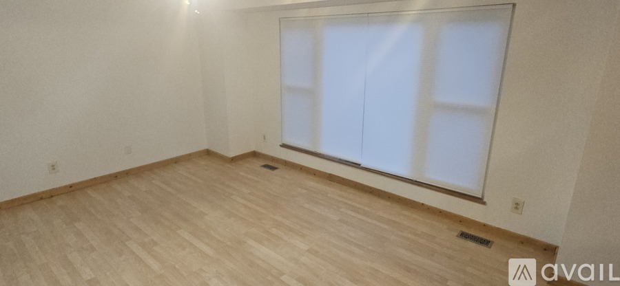 A room with wooden flooring and a large window.