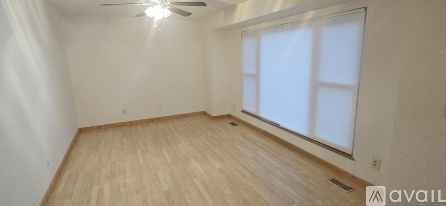 A room with wooden flooring and a window with blinds.