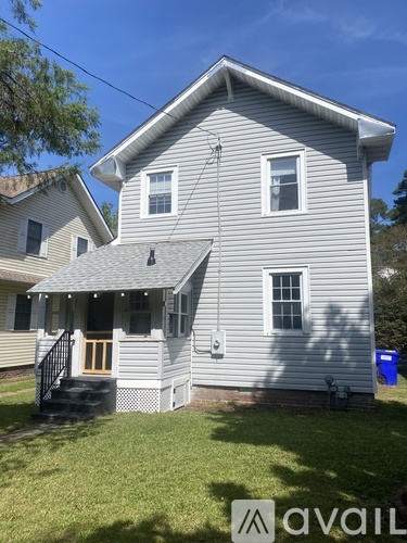 A house with a grey siding and a white window is shown.