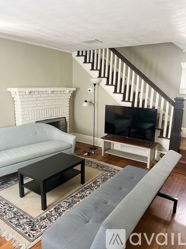 A living room with a grey couch, a black coffee table, and a white fireplace.