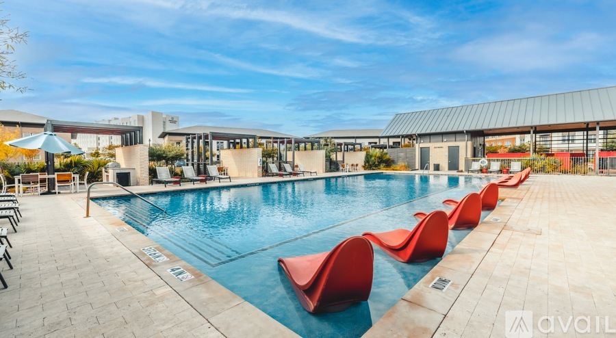A pool with red chairs and a blue sky in the background.