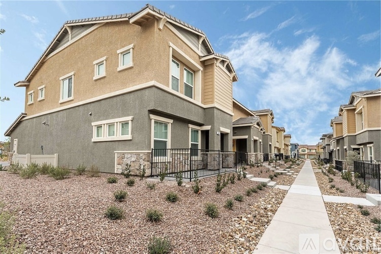 A modern house with a grey front yard and a black fence.