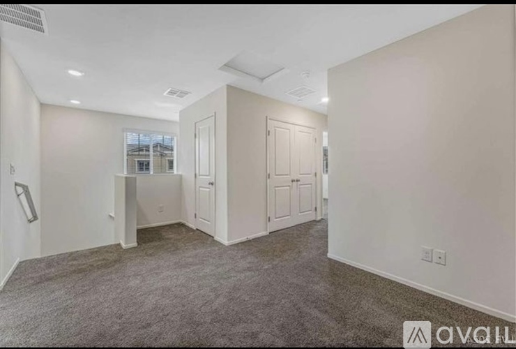 A spacious room with a carpeted floor and white walls.