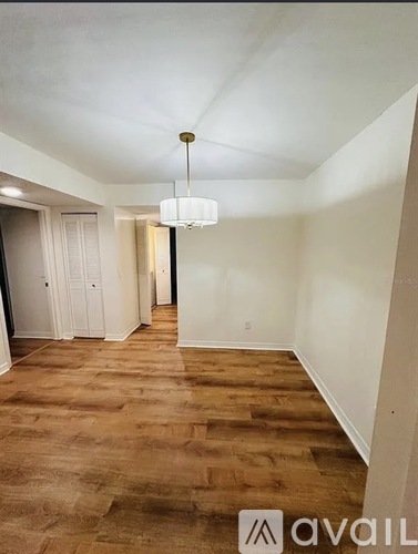 A room with wooden flooring and a chandelier hanging from the ceiling.