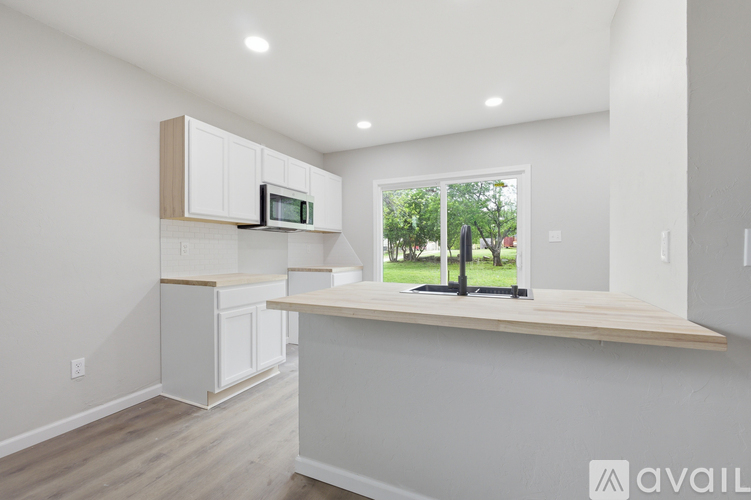 A kitchen with white cabinets and a wooden countertop.