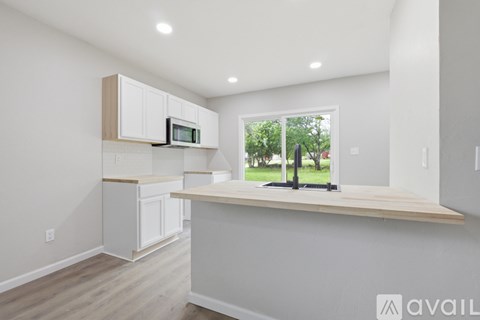 A kitchen with white cabinets and a wooden countertop.