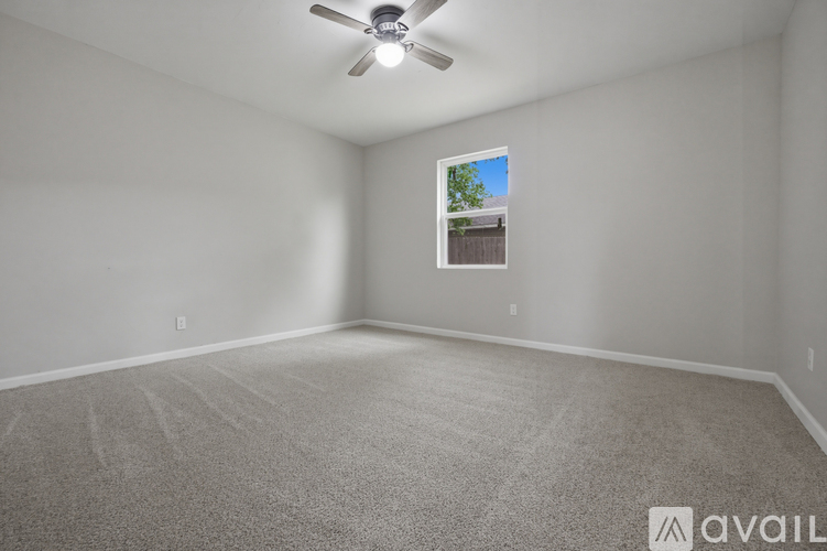 A room with a ceiling fan and a window showing a tree and a building outside.