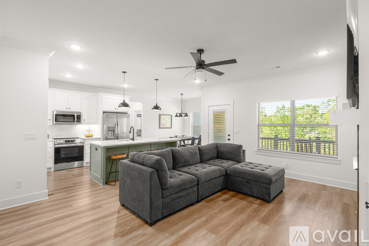A modern kitchen with a grey couch and a ceiling fan.
