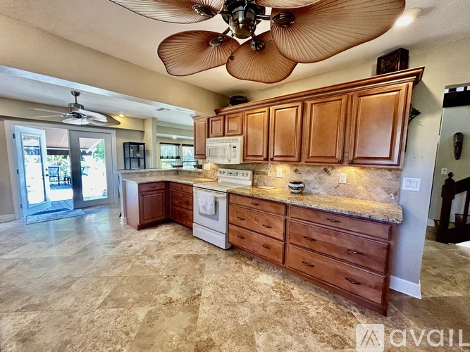 A kitchen with a fan and wooden cabinets.
