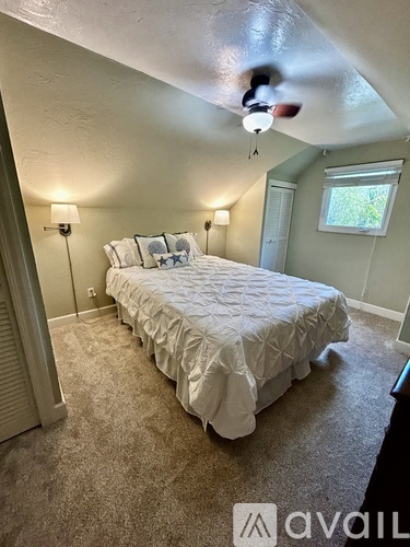 A bedroom with a large bed and two lamps.