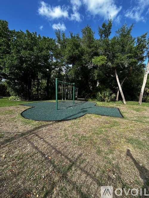 A playground with a green swing set and a blue sky.