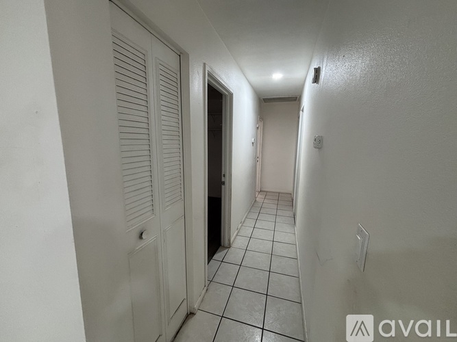 A hallway with white walls and a tiled floor.