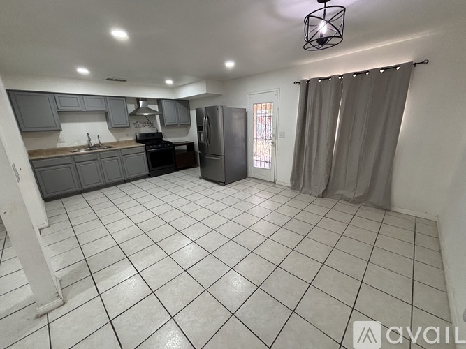 A kitchen with a refrigerator, sink, and cabinets.