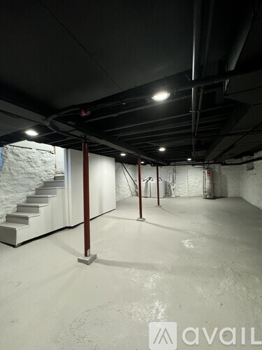 A spacious, empty basement with a staircase and a concrete floor.