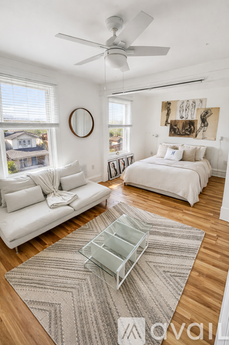 A bedroom with a white bed and a white couch.