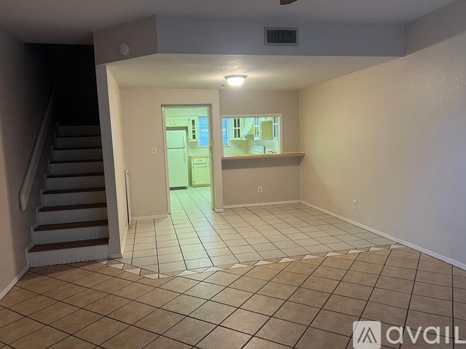 A room with tiled flooring and a staircase leading to another room.